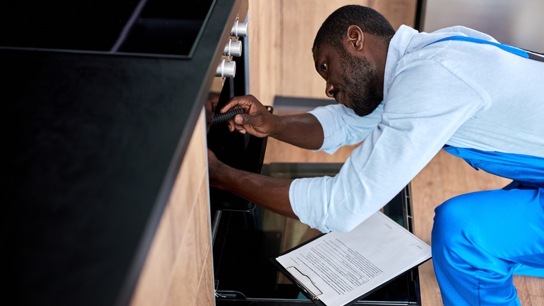 repair man looking inside oven