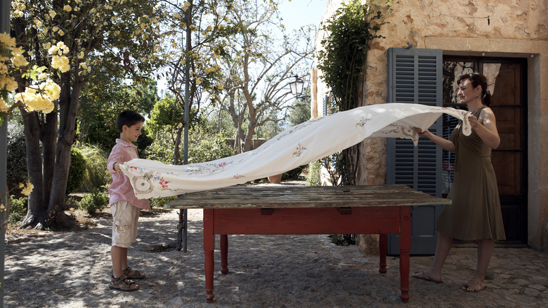 mom and son placing tablecloth on table