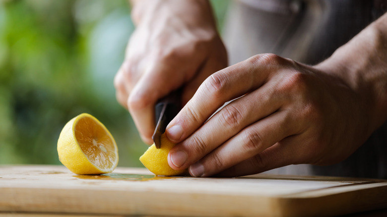 Hands chopping lemon in two