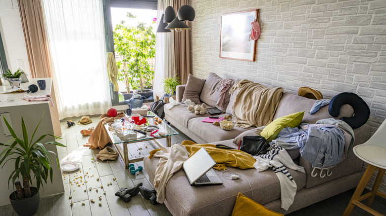 Living room filled with clutter, clothes strewn everywhere