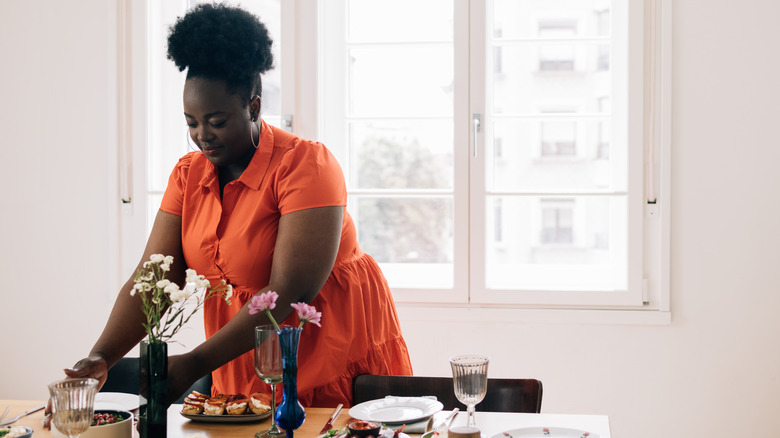 Woman in orange dress decorating table for guests