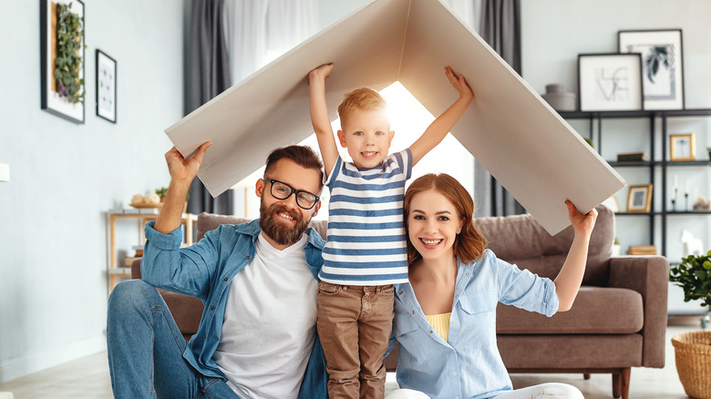 family under cardboard roof inside