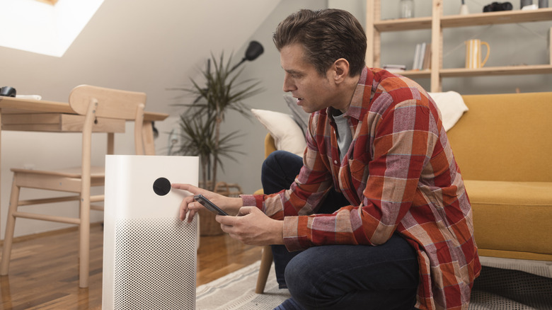 A man setting up an air purifier in a living room setting