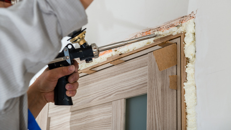 Person spraying insulation foam doorway