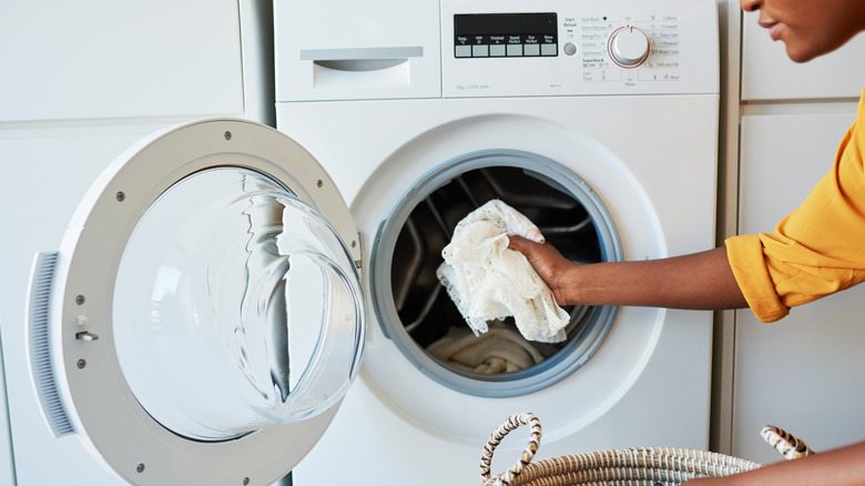 Woman putting white laundry into the machine