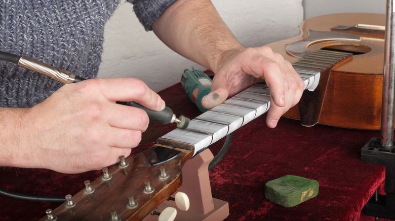 Person using a rotary tool with a foot pedal to repair guitar