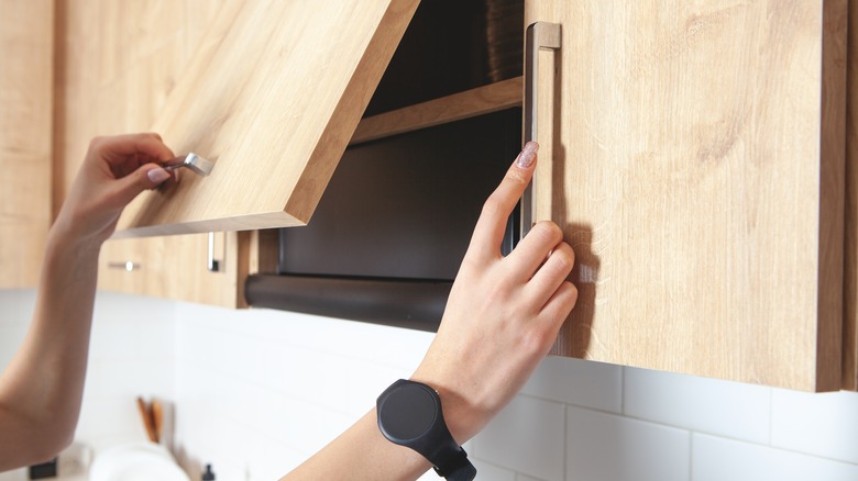 Hands opening kitchen cabinets