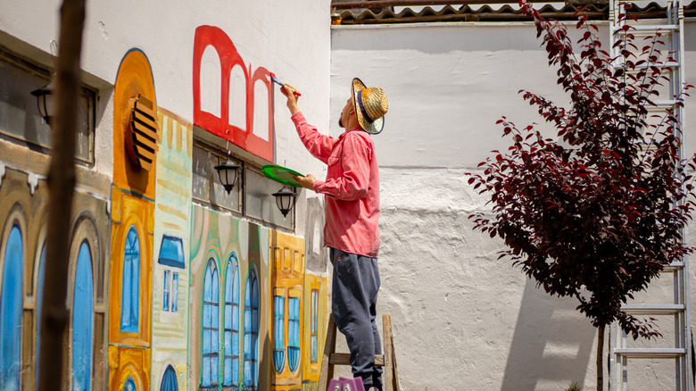 Someone painting a mural outside of their home