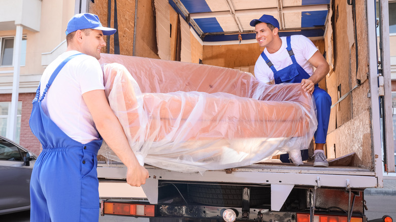 Two men unload couch from truck