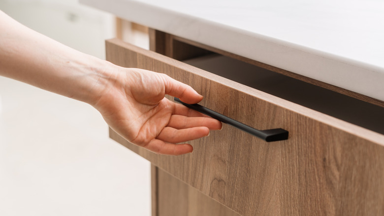 A hand opening up a kitchen drawer