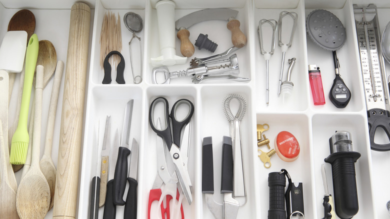 A well organized kitchen drawer with dividers and many kitchen tools and gadgets