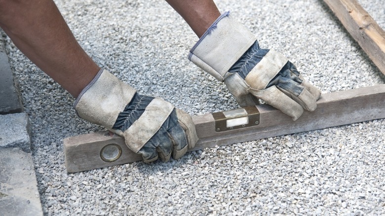 A person leveling gravel for a paver base