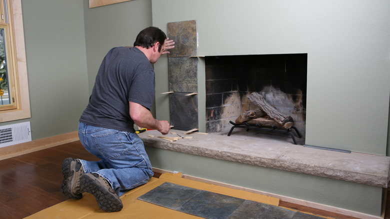 man installing fireplace tile