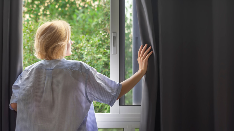 Woman at window with blackout curtains