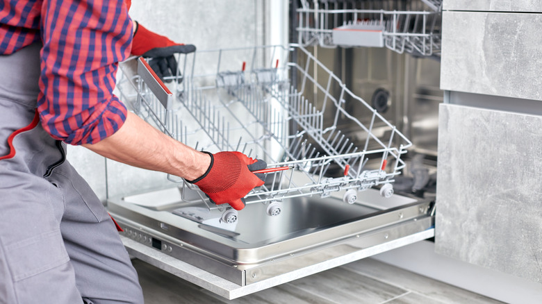 Repair person installing dishwasher drawer