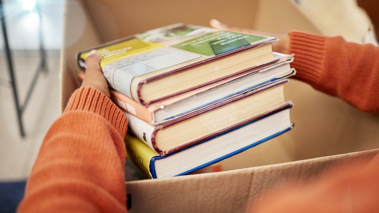 A person holds a pile of old books.