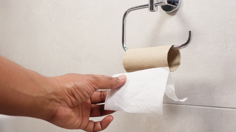 A person pulls on an empty toilet paper roll