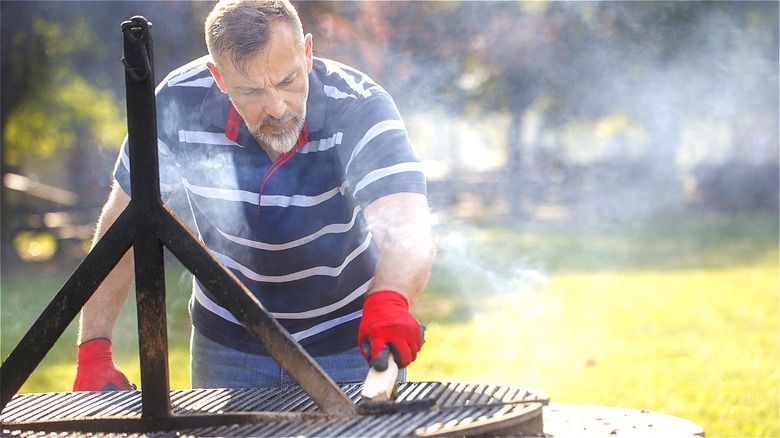 Person scrubbing hot grill outdoors