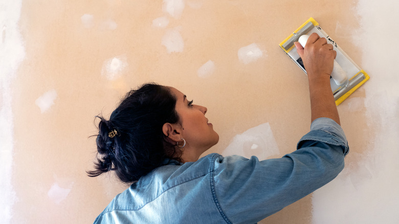 Woman sanding a wall