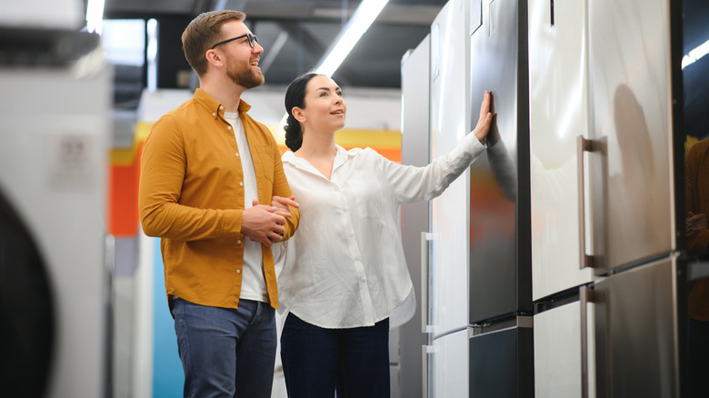 Man and woman looking at refrigerators