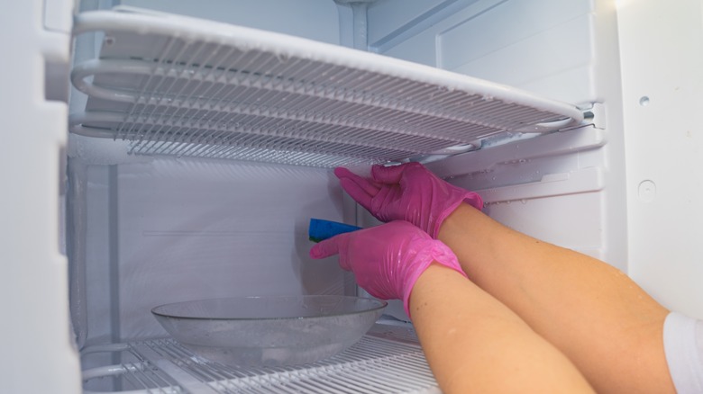 Person wiping down freezer vent