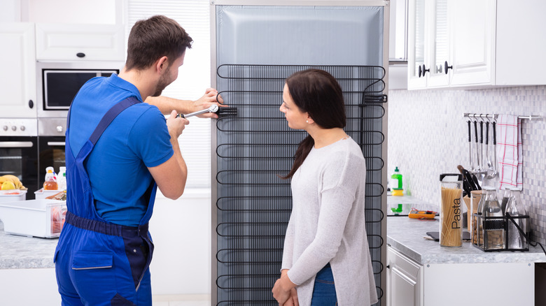 Technician showing person fridge coils