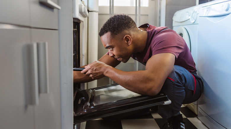 Man fixing an oven with tools