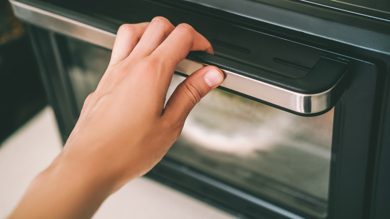 Hand opening an oven