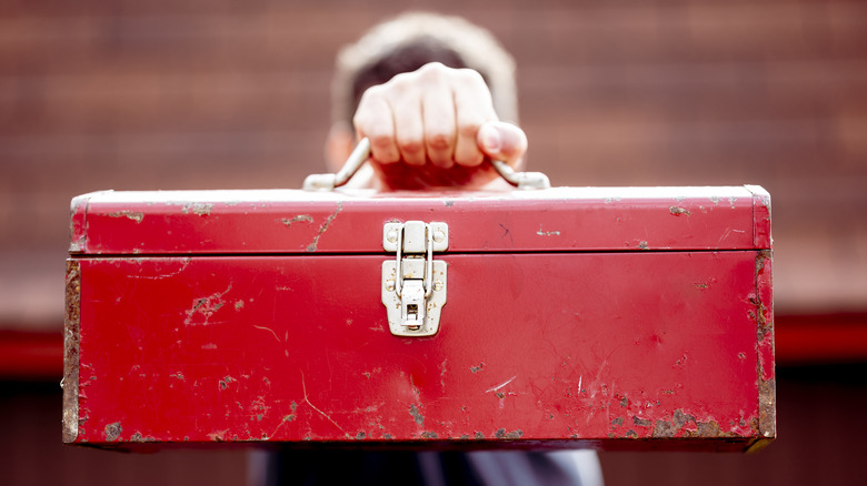 person holding red toolbox