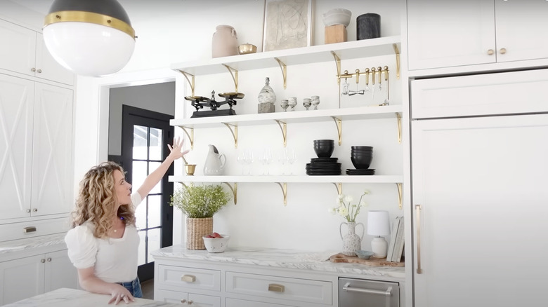 woman showing white open shelf kitchen