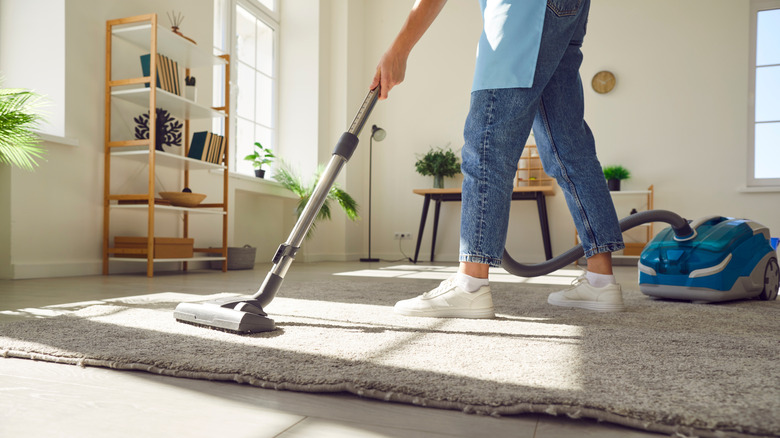 Woman vacuuming rug in a modern home