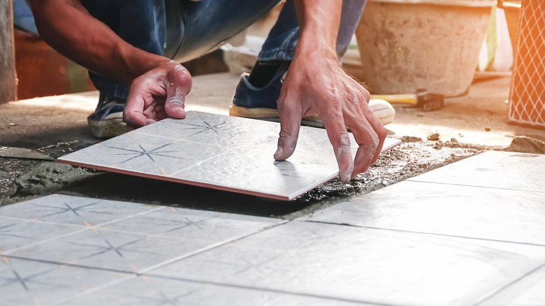 Man placing square tile