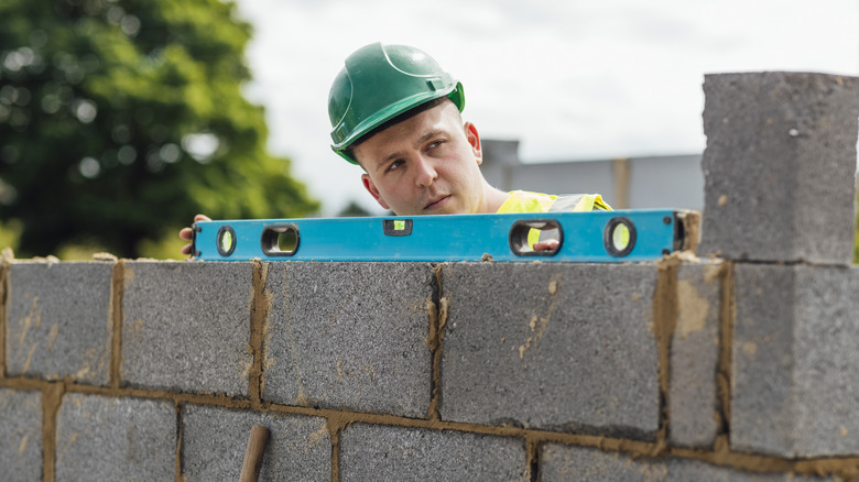 A man building a wall using concrete blocks