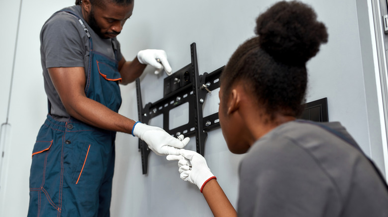 two people attaching TV mount