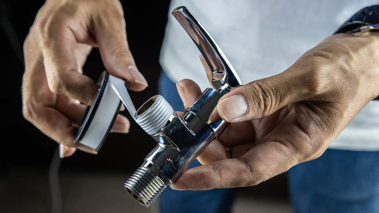 Person wrapping silver faucet with plumber's tape