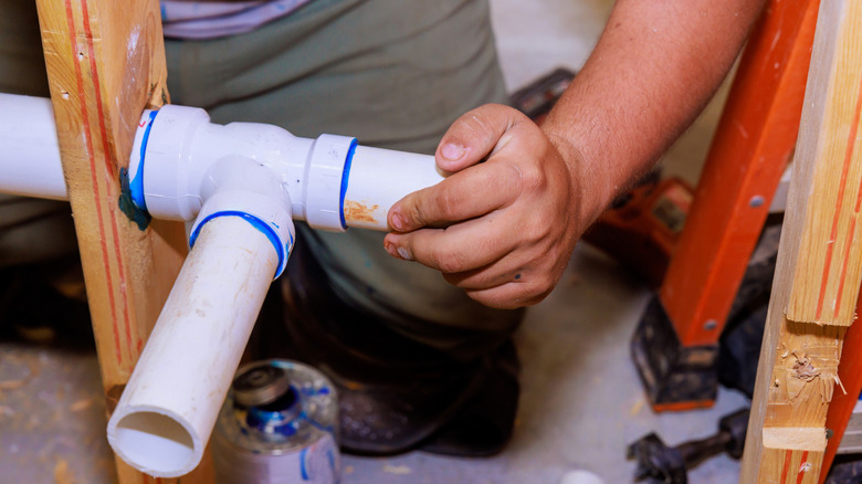 A plumber holding glued pvc pipes together firmly with left hand
