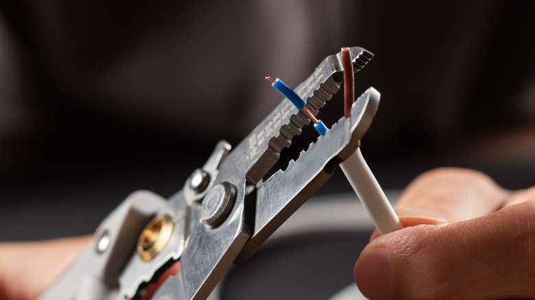 Person using a wire stripper to remove insulation from a wire