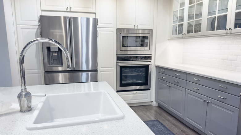 A kitchen with cold finishes of stainless steel, gray, and white