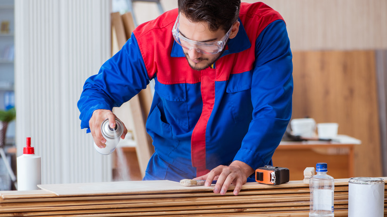 person spray painting wood