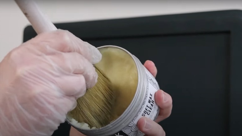 person putting wax on brush