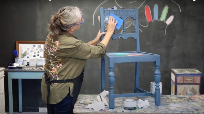 woman sanding painted chair