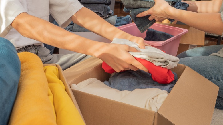 person packing up decluttered clothes into donation box