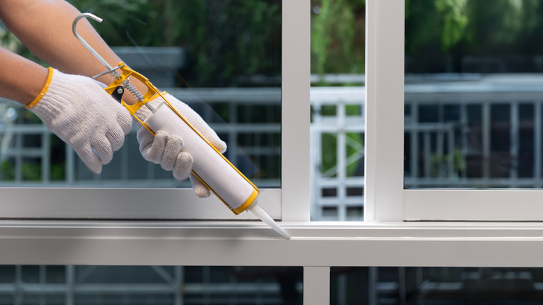 A worker seals a gap on a window