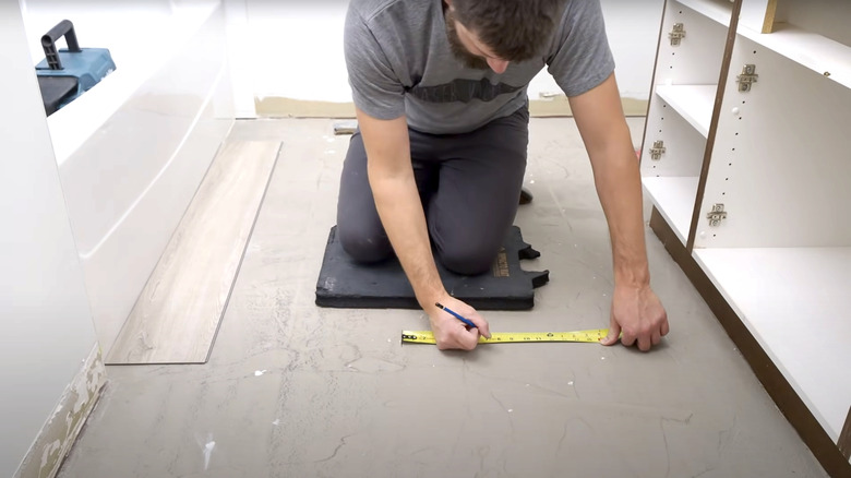 bearded man measuring floor for new vinyl installation