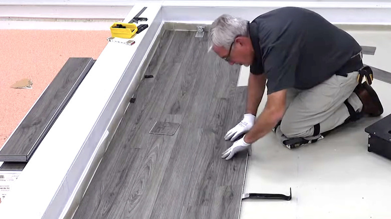 man laying different gray vinyl planks