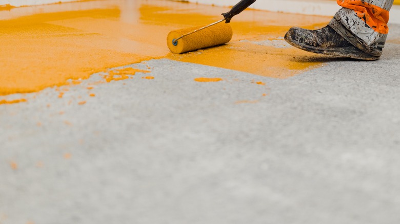 Person painting concrete orange