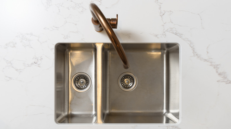 clean double sided stainless steel sink with white marble countertops