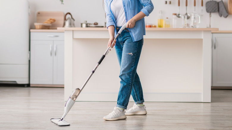 Woman steam mops laminate floors