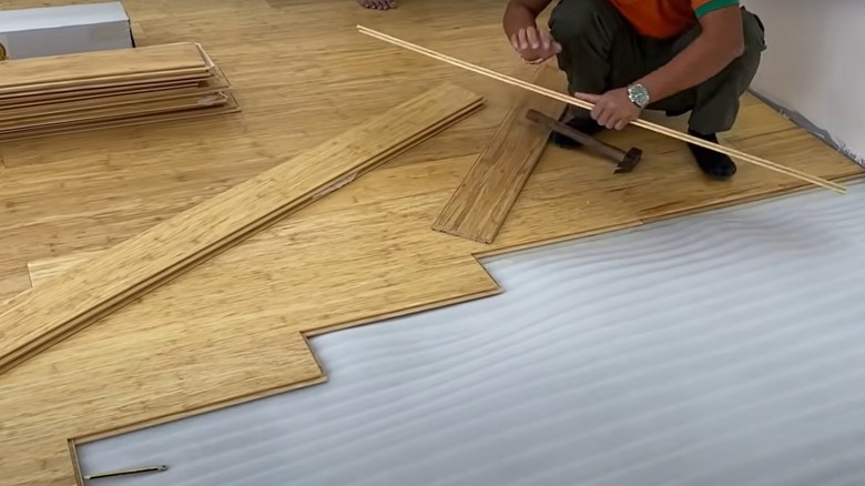 A person installing bamboo flooring in a home