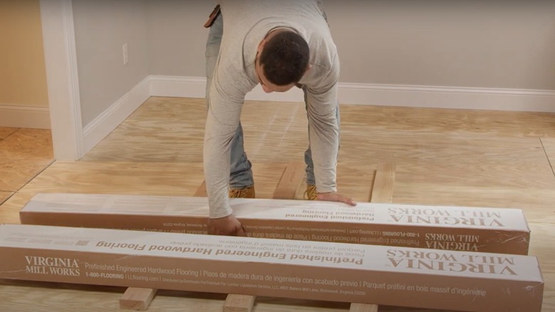 A man setting up boxes of hardwood flooring to acclimate it before installation